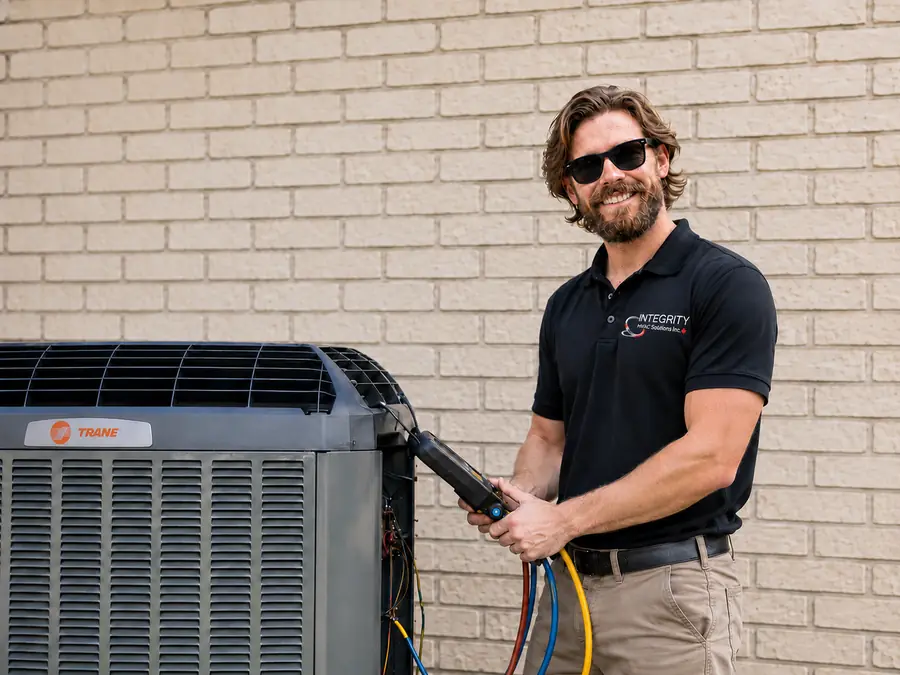 An Integrity HVAC Solutions technician smiling while servicing a heat pump