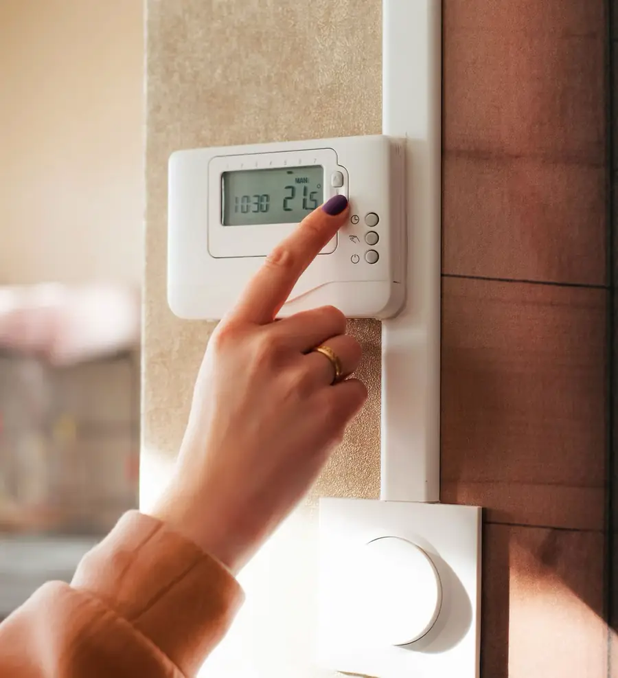 A homeowner setting their thermostat to a comfortable 21 degrees